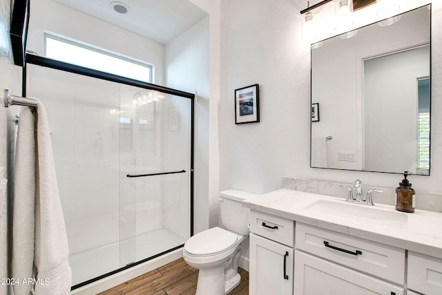 bathroom featuring wood-type flooring, vanity, a shower with shower door, and toilet