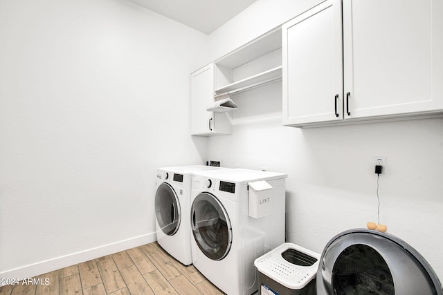 laundry area with cabinets, light hardwood / wood-style floors, and washing machine and dryer