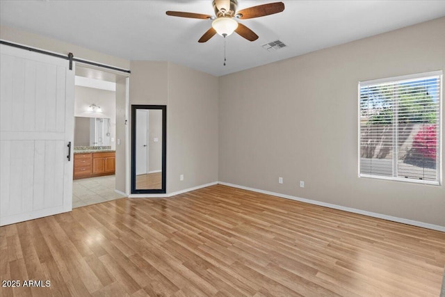 21192 E Stirrup St, Queen Creek, AZ 85142 - empty room with light wood-style flooring, a barn door, visible vents, baseboards, and a ceiling fan
