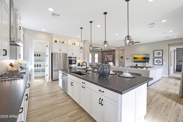 kitchen featuring sink, white cabinetry, hanging light fixtures, an island with sink, and stainless steel appliances