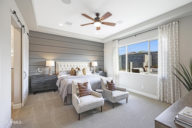 bedroom featuring wooden walls, ceiling fan, a barn door, and light carpet