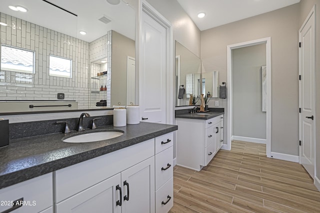 bathroom with walk in shower, vanity, and backsplash