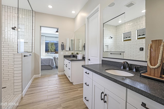 bathroom featuring ceiling fan, tiled shower, wood-type flooring, and vanity