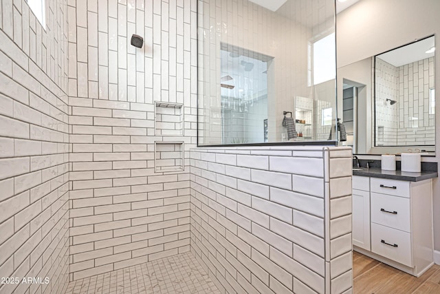 bathroom with hardwood / wood-style flooring, vanity, and tiled shower