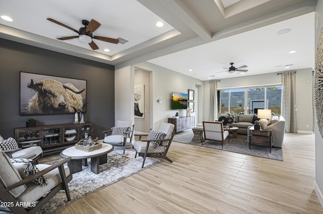 living room featuring ceiling fan, a tray ceiling, and light hardwood / wood-style floors