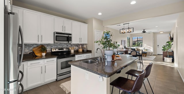 kitchen with stainless steel appliances, backsplash, open floor plan, a sink, and tile patterned flooring