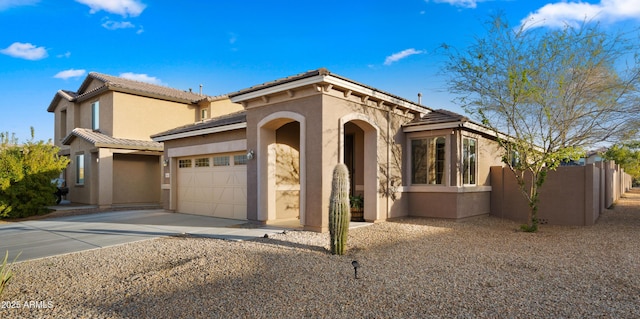 mediterranean / spanish home featuring driveway, a garage, a tile roof, fence, and stucco siding