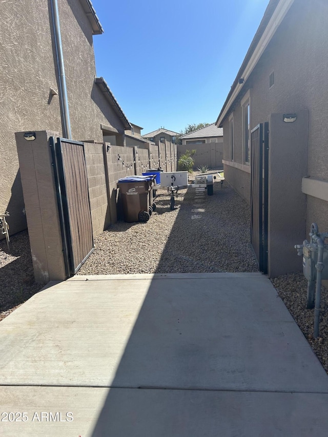 view of side of home with a patio area, a fenced backyard, and stucco siding