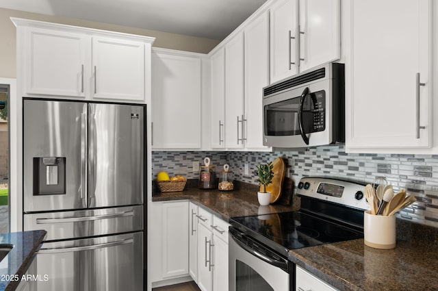 kitchen with stainless steel appliances, white cabinetry, dark stone countertops, and tasteful backsplash