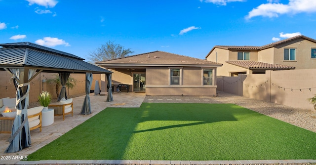 rear view of house with a patio, stucco siding, a lawn, a gazebo, and a fenced backyard