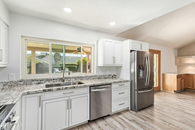 kitchen featuring appliances with stainless steel finishes, a sink, light stone countertops, and white cabinets