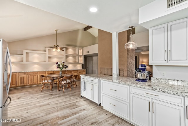 kitchen featuring visible vents, white cabinetry, hanging light fixtures, stainless steel refrigerator, and light stone countertops