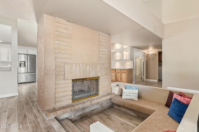 unfurnished living room featuring wood finish floors, a large fireplace, and baseboards