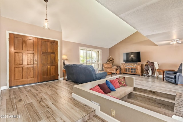 living room with lofted ceiling, baseboards, and wood finished floors