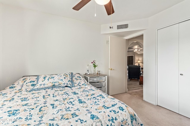 bedroom with a ceiling fan, a closet, visible vents, and light colored carpet