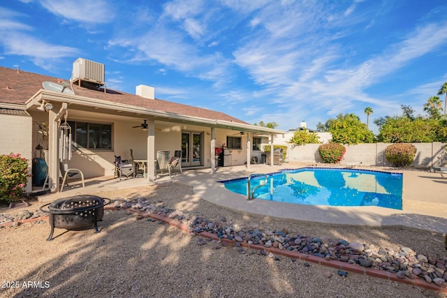 view of swimming pool featuring cooling unit, a fenced backyard, a fire pit, a ceiling fan, and a patio area