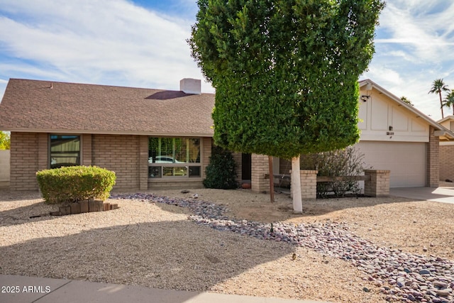 view of front of property with an attached garage, a shingled roof, concrete driveway, and brick siding