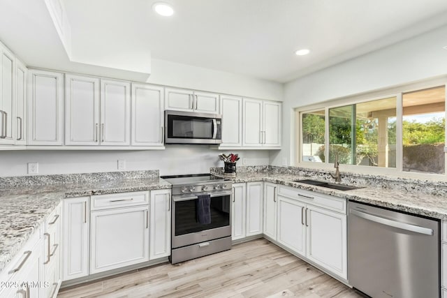 kitchen featuring recessed lighting, light wood-style floors, white cabinets, appliances with stainless steel finishes, and light stone countertops