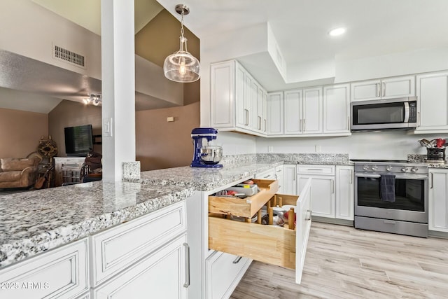 kitchen featuring white cabinets, appliances with stainless steel finishes, light stone counters, light wood-style floors, and pendant lighting