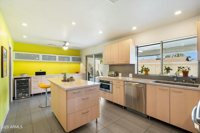 kitchen with wine cooler, a kitchen island, sink, appliances with stainless steel finishes, and light brown cabinets