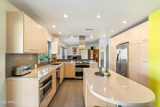 kitchen with kitchen peninsula, island exhaust hood, light stone countertops, stainless steel appliances, and light tile patterned floors