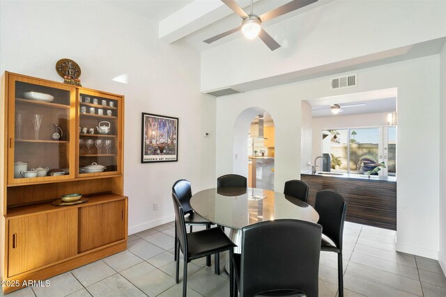 tiled dining room with ceiling fan and beamed ceiling