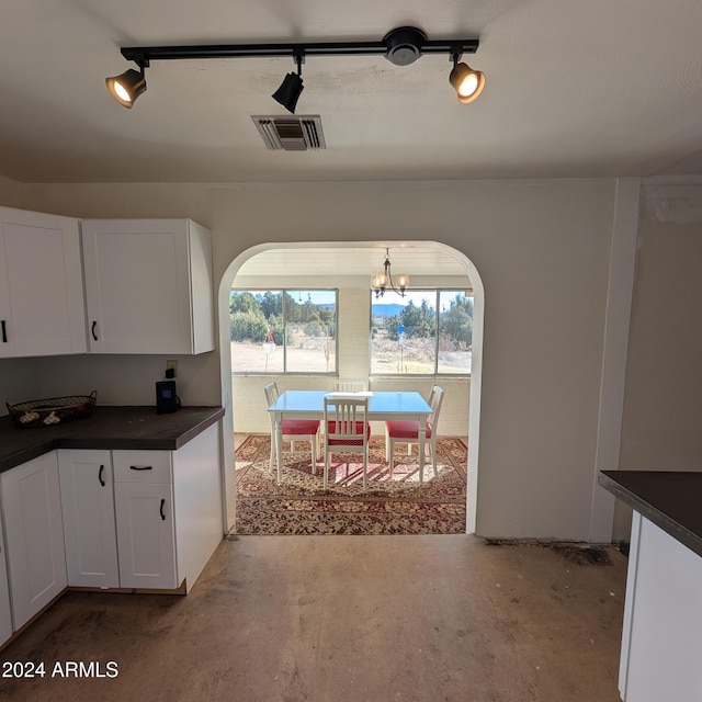 dining space featuring unfinished concrete floors, arched walkways, visible vents, and a chandelier