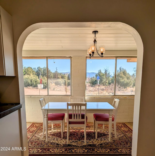 dining area featuring arched walkways, brick wall, and a chandelier