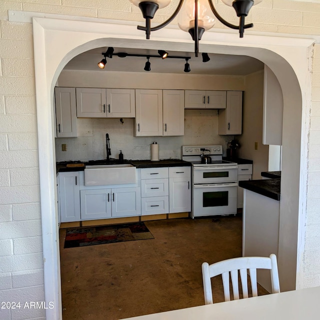 kitchen with dark countertops, concrete floors, range with two ovens, arched walkways, and a sink