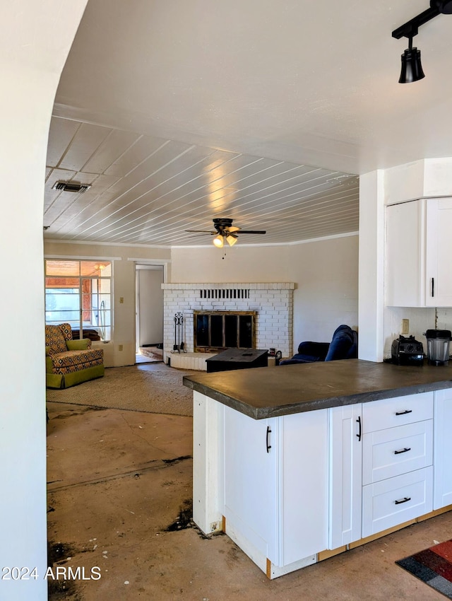 kitchen featuring dark countertops, ceiling fan, open floor plan, a fireplace, and white cabinetry