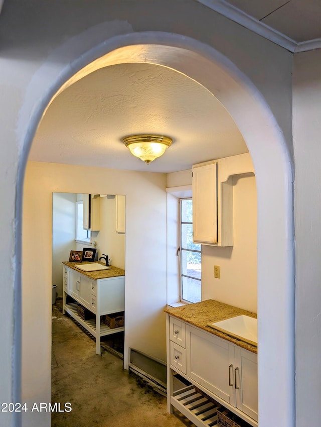 interior space with a sink, arched walkways, and ornamental molding