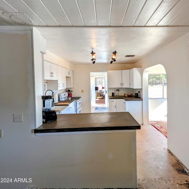 kitchen featuring range with two ovens, dark countertops, a peninsula, and white cabinetry