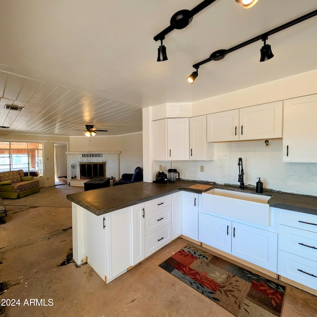 kitchen featuring a sink, dark countertops, white cabinets, and a fireplace