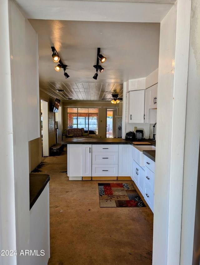 kitchen featuring white cabinetry, dark countertops, a peninsula, and ceiling fan