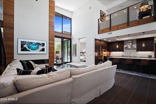 living room featuring a towering ceiling, a fireplace, and sink