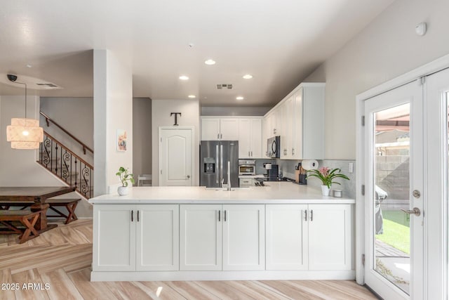 13540 N 87th Dr, Peoria, AZ 85381 - kitchen with stainless steel fridge with ice dispenser, a peninsula, light countertops, white cabinets, and backsplash