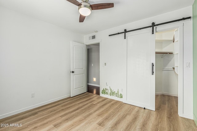 18820 N 33rd Ave, Phoenix, AZ 85027 - unfurnished bedroom featuring light wood-style flooring, a walk in closet, a barn door, a closet, and a ceiling fan