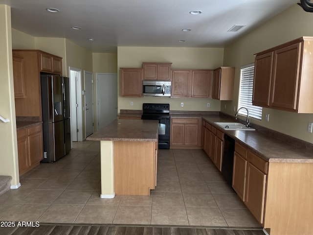 kitchen with black appliances, a center island, light tile patterned flooring, and sink