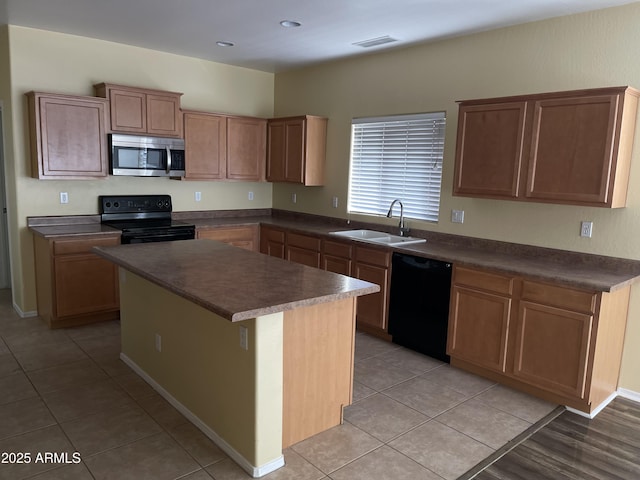 kitchen featuring light tile patterned floors, sink, a center island, and black appliances