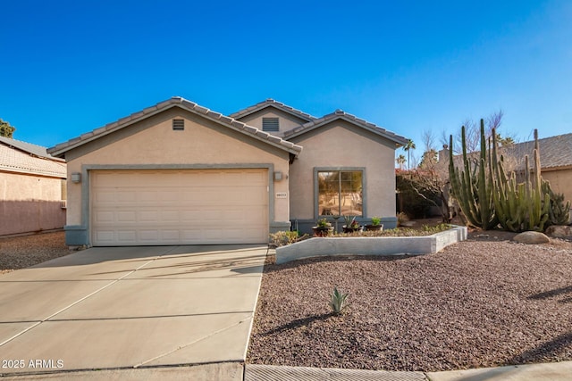 view of front of house with a garage, concrete driveway, a tiled roof, and stucco siding