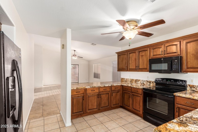 kitchen with brown cabinets, vaulted ceiling, black appliances, and light stone countertops