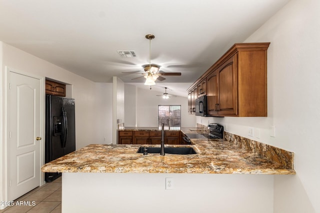 kitchen with light stone counters, visible vents, a sink, a peninsula, and black appliances