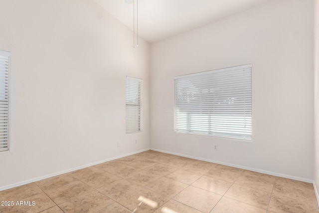 spare room with vaulted ceiling and light tile patterned floors