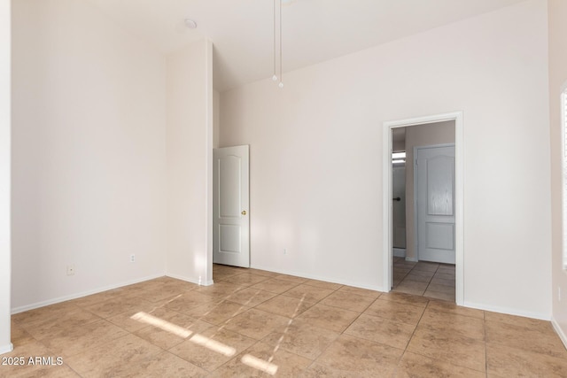 unfurnished bedroom with ensuite bathroom, tile patterned floors, and baseboards