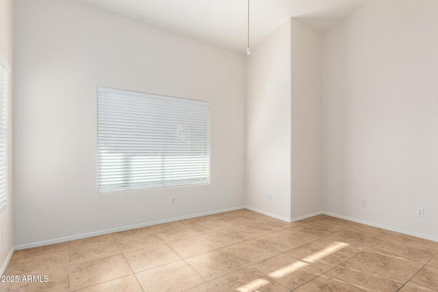 empty room with light tile patterned floors and baseboards