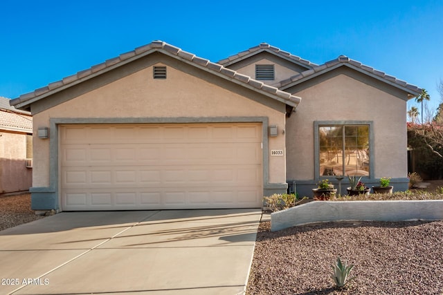 view of front of house featuring an attached garage, driveway, a tiled roof, and stucco siding