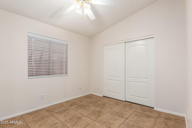 unfurnished bedroom with ceiling fan, light tile patterned flooring, baseboards, vaulted ceiling, and a closet