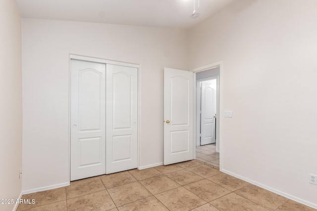 unfurnished bedroom featuring baseboards, a closet, and light tile patterned flooring