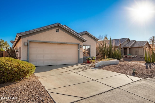 ranch-style home with concrete driveway, a tiled roof, an attached garage, and stucco siding