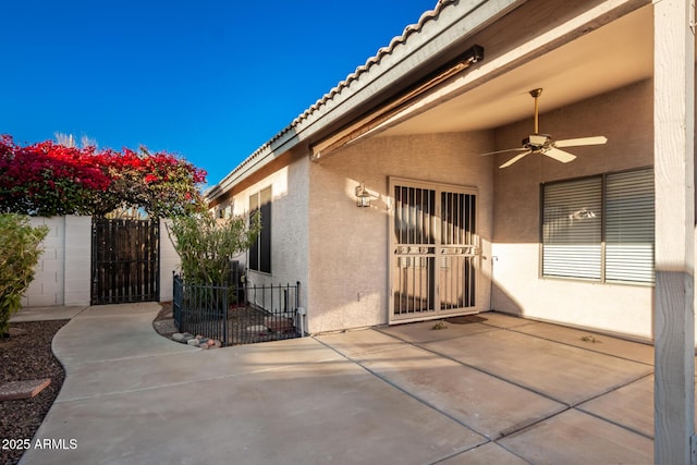 exterior space with a patio, ceiling fan, a tiled roof, fence, and stucco siding